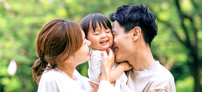 子供の顔に母親と父親が顔を寄せて笑っている写真