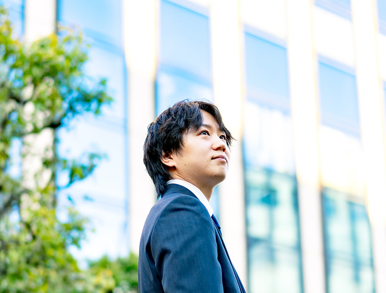 ビルの前で空を見上げる本社総合職の男性