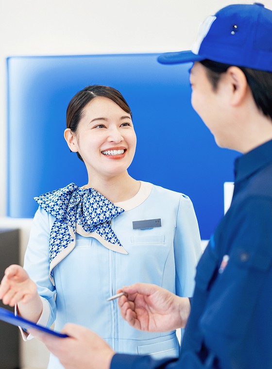 帽子を被った人と笑顔で話すフロントスタッフの女性