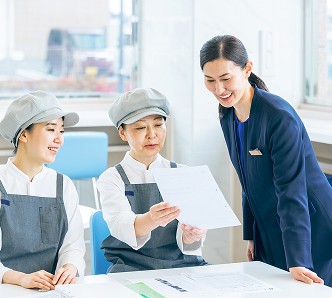 明るい社内で朝食スタッフと楽しく会話する支配人の女性